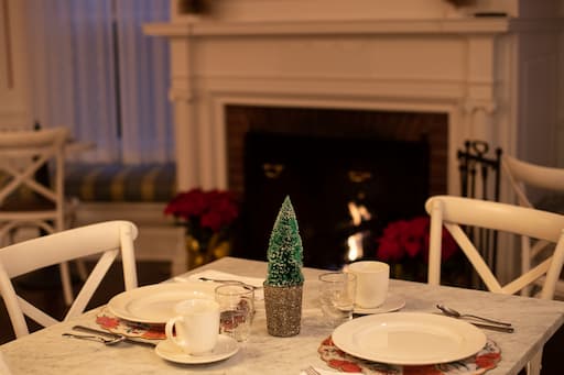 A dining table next to the lit fireplace in our dining room at our New England bed and breakfast