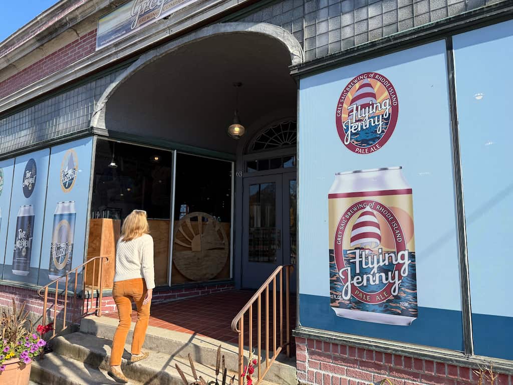 A woman walking into the entrance of Grey Sail Brewing of Rhode Island