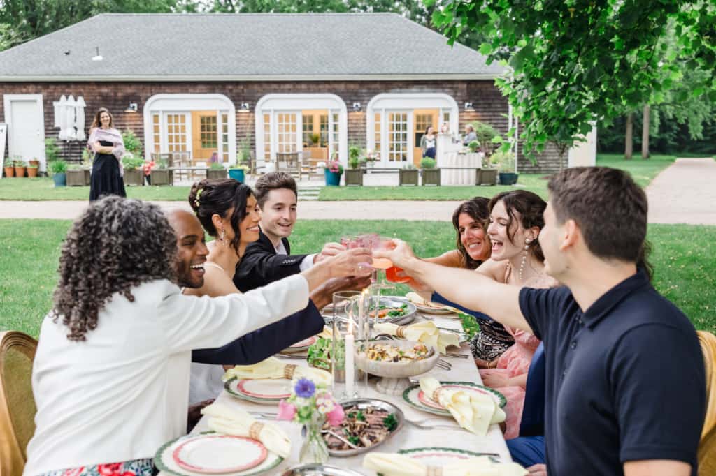 A group of friends at a table toasting to the bride and groom after their micro wedding ceremony