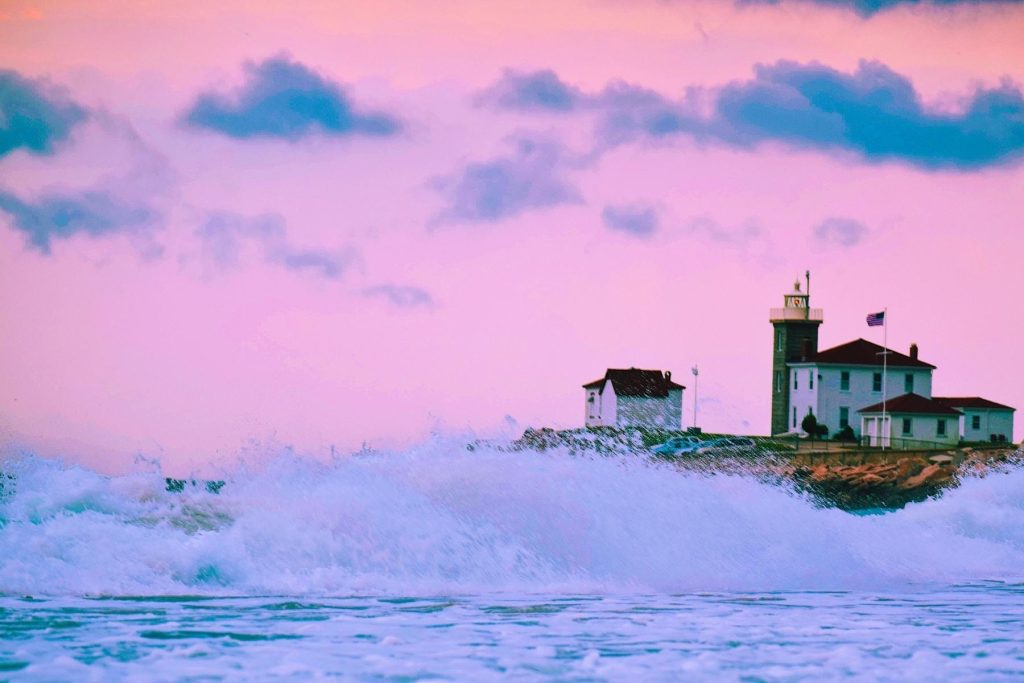 Waves crashing in front of the Watch Hill Lighthouse during sunset