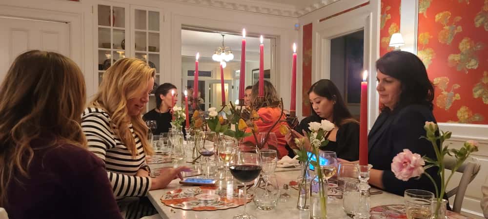 A group of women enjoying a candlelit dinner at a long table during a weekend getaway at Margin Street Inn in New England.