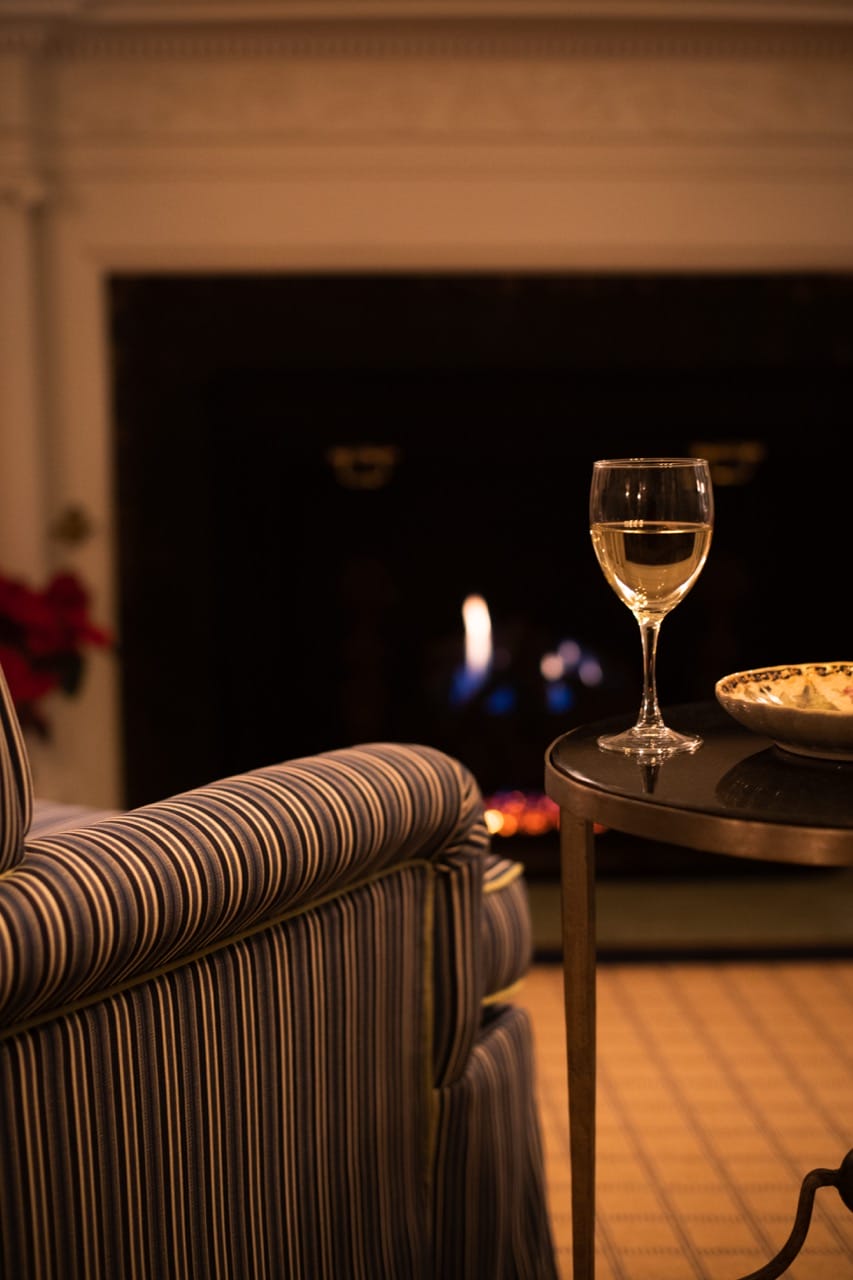 A glass of wine and an armchair in front of the fireplace at our New England bed and breakfast